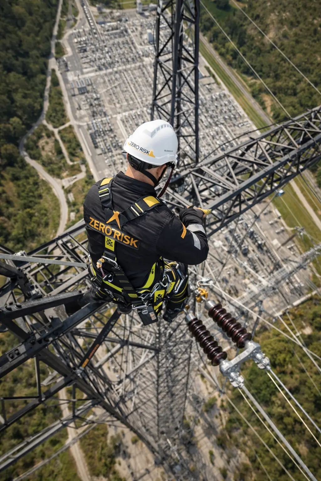 Técnico de Zero Risk con arnés trabajando en altura sobre una torre eléctrica